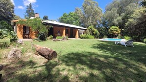 A house with a swimming pool, surrounded by a well-maintained lawn and trees.