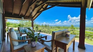 An outdoor seating area with wooden furniture and a view of the landscape. - Fascinante rancho (personal de servicio incluido) (Jarabacoa)