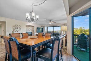 A spacious dining area with a large wooden table and woven chairs, a chandelier, and a view of the outdoors. - Hot Springs Vacation Rental w/ Game Room! (Hot Springs)