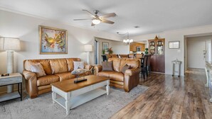 A spacious living room with a brown leather sofa, a wooden coffee table, and a ceiling fan. - Hot Springs Vacation Rental w/ Game Room! (Hot Springs)