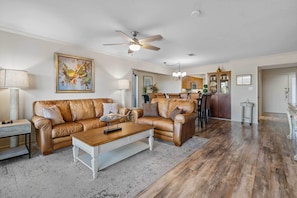 A spacious living room with a brown leather sofa, a wooden coffee table, and a ceiling fan. - Hot Springs Vacation Rental w/ Game Room! (Hot Springs)