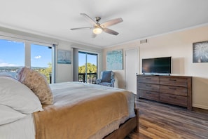 A bedroom with a large bed, a ceiling fan, a TV, and a balcony with a chair. - Hot Springs Vacation Rental w/ Game Room! (Hot Springs)
