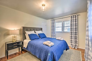 A bedroom with a bed, nightstand, and a window with curtains.