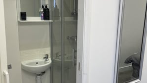 A bathroom with a white sink, a glass shower enclosure, and a mirror above the sink.
