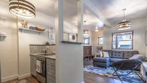 Eine moderne Küche mit Einbauofen und Essbereich mit grauem Sofa und gemustertem Teppich.