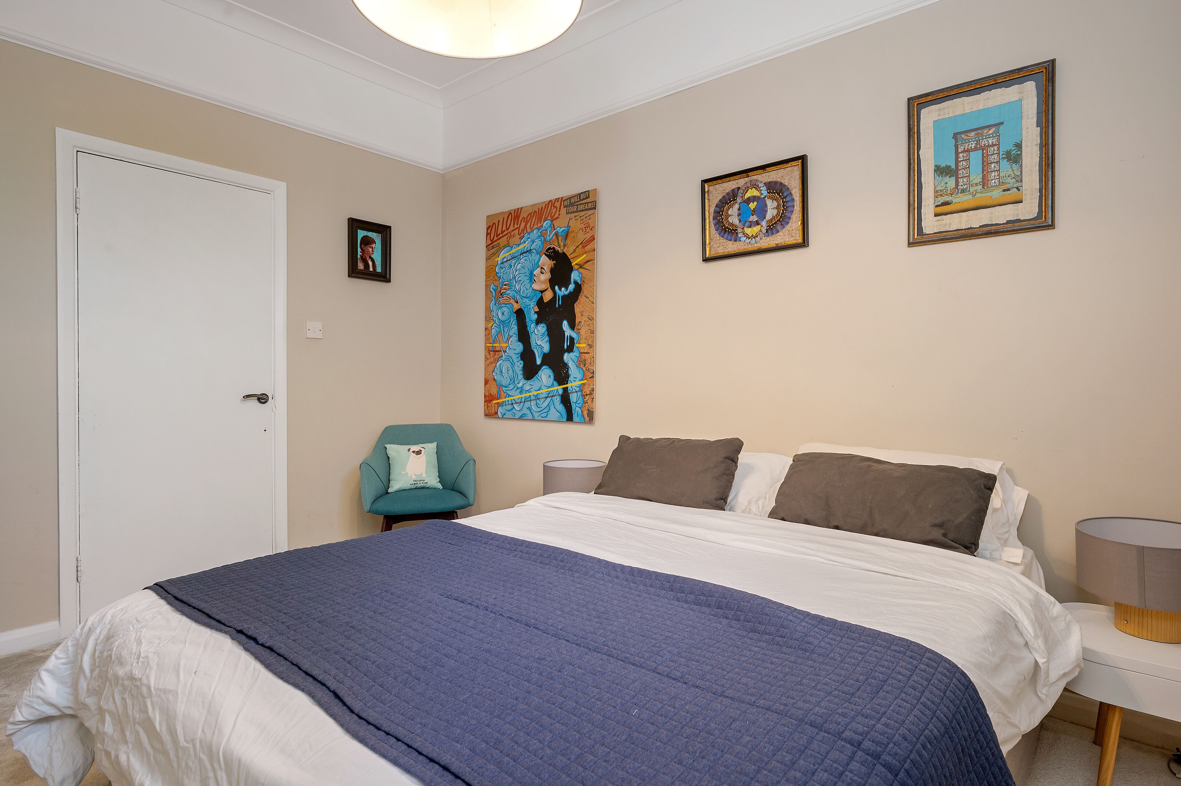 A bedroom with a large bed, a chair, and two wall-mounted lamps.