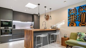Une cuisine moderne dotée d’un îlot central, de tabourets de bar et d’un coin repas comprenant un canapé et une table.