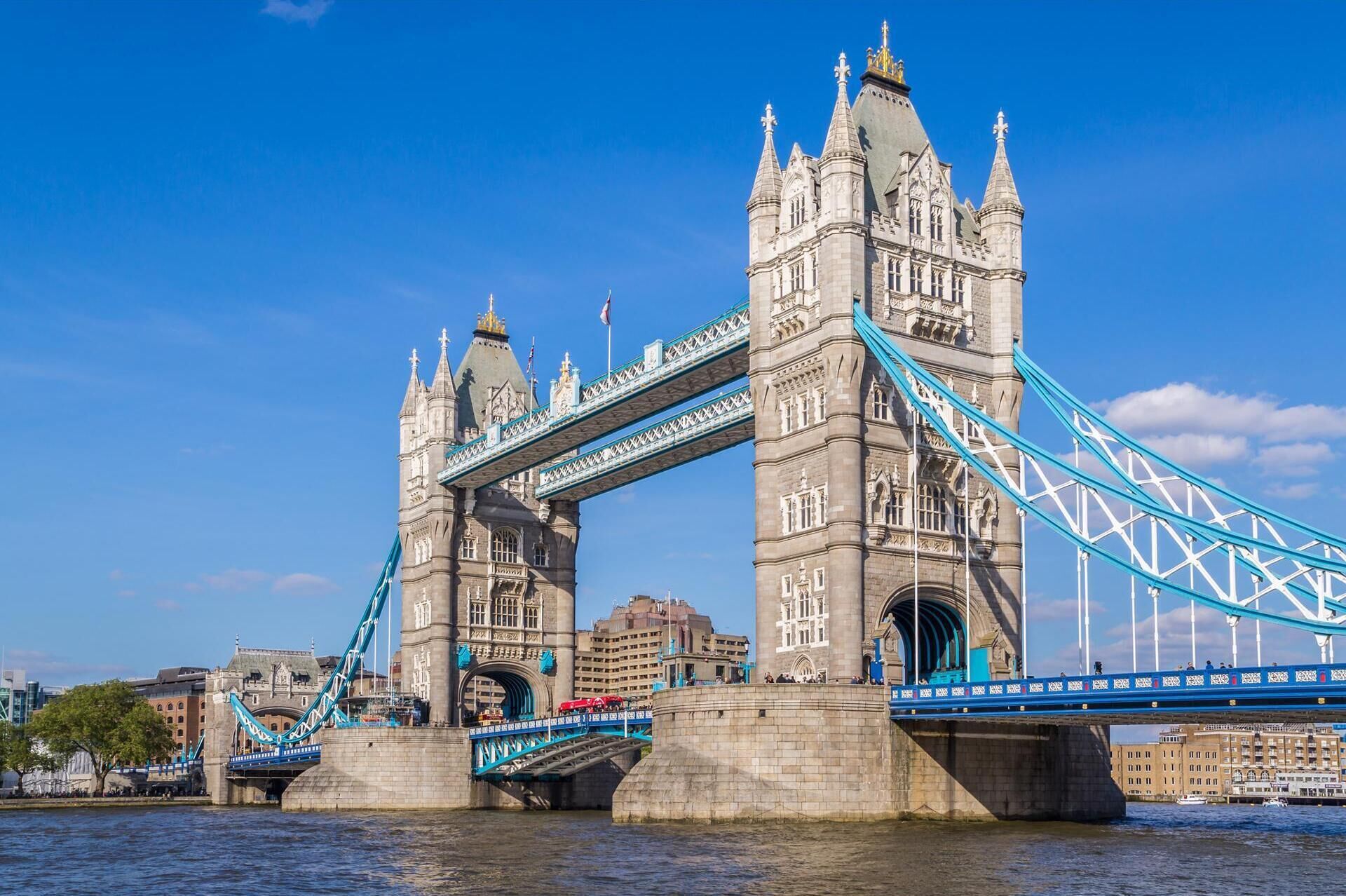 A large stone bridge with two towers and a blue suspension cable.