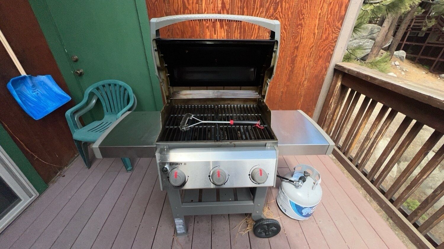 Ein Grill im Freien mit Gasflasche und einem Metalltisch daneben.