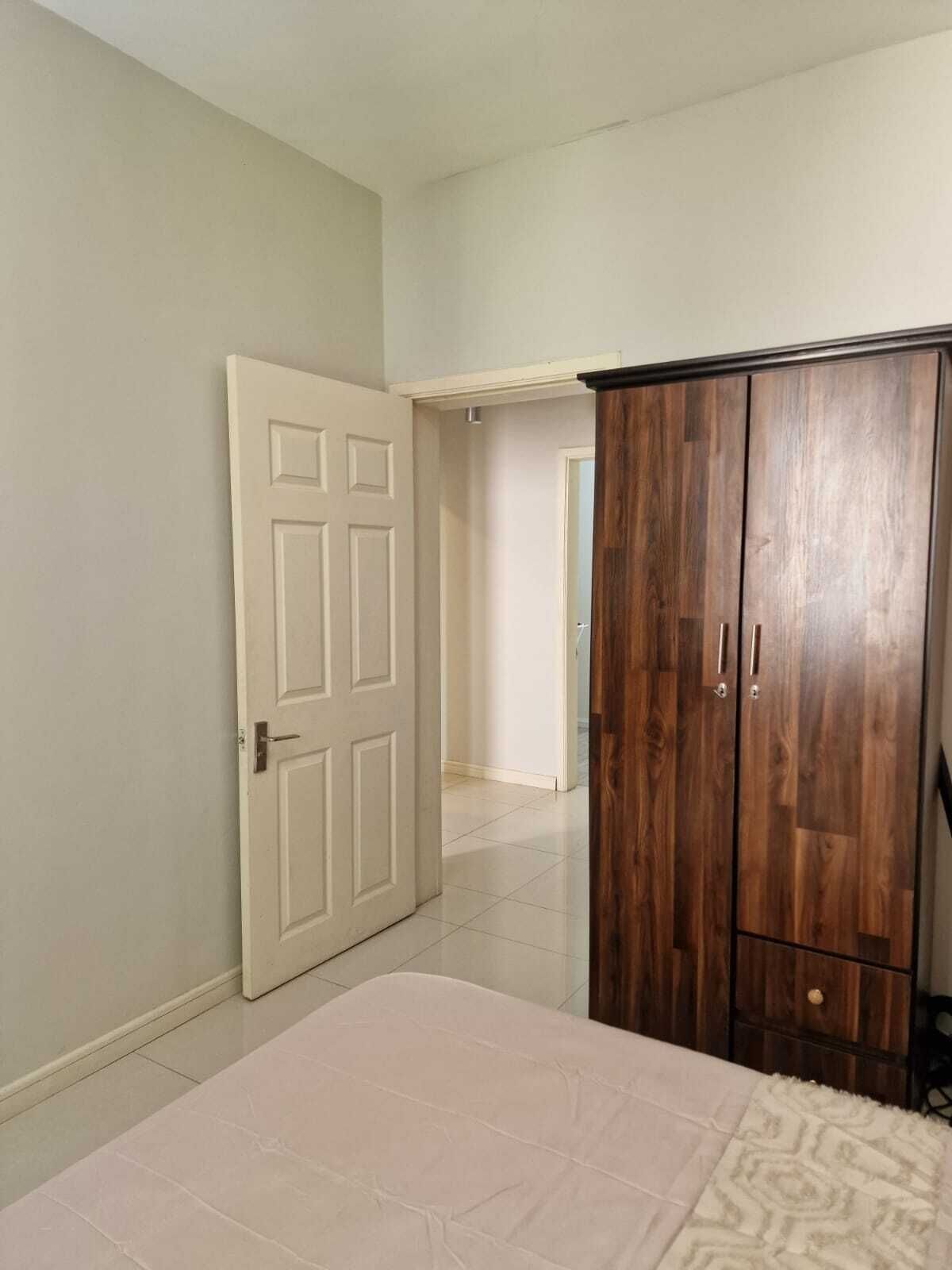 Une chambre à coucher comprenant un lit, une armoire et une porte donnant sur une autre pièce.