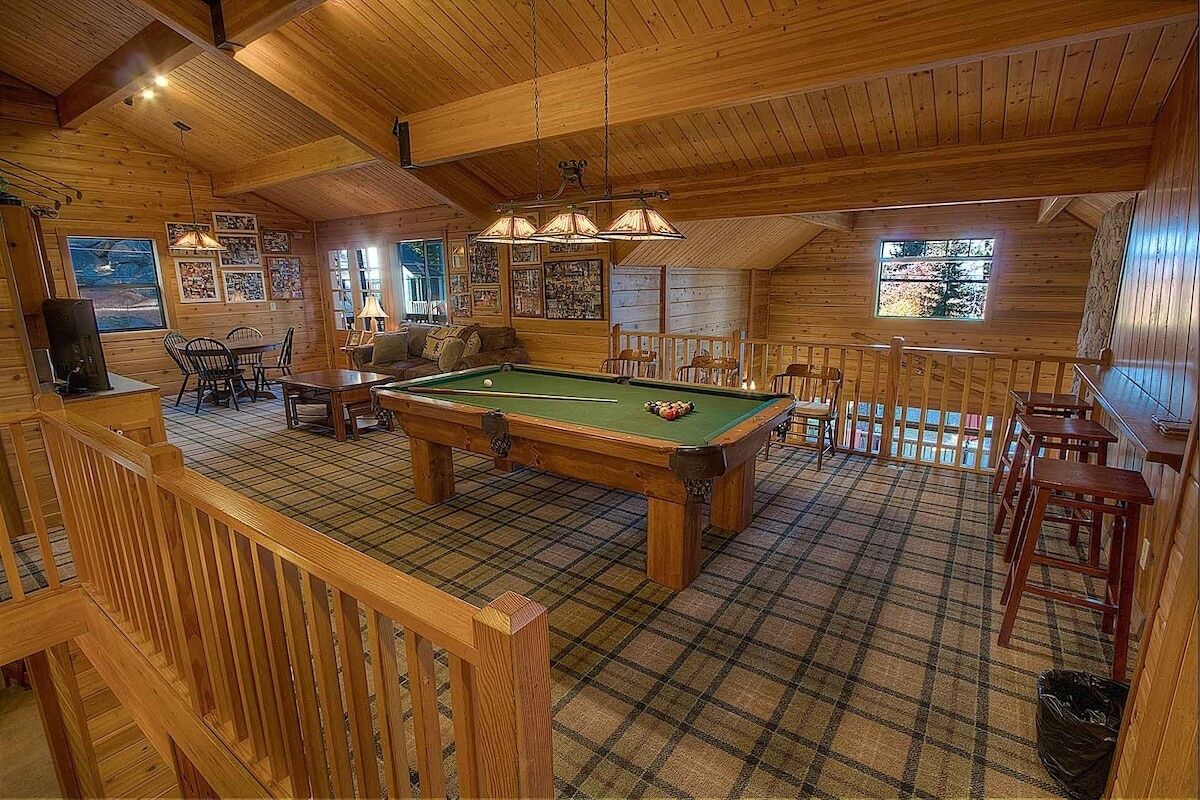 Un espace intérieur chaleureux et accueillant, avec une table de billard, des meubles en bois et un sol à carreaux.