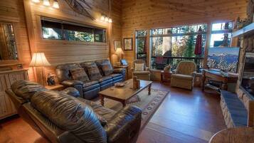 A cozy cabin interior with a leather sofa, wooden coffee table, and a fireplace.