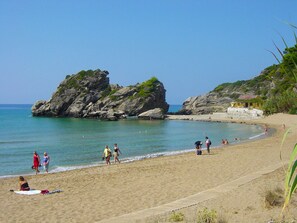 A beach with rocky formations and a clear sky.