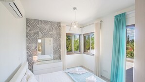 Een moderne slaapkamer met een muur met zebraprint, een groot bed met een blauwe spreidek en een hanglamp, plus uitzicht op groen door het raam.