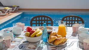 A dining table with breakfast items, a glass of orange juice, and a poolside setting. - Modern villa near beach [86] (Lagos)