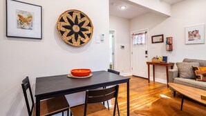 Un comedor con una mesa y sillas negras, un adorno de pared tejido y un cuadro enmarcado.