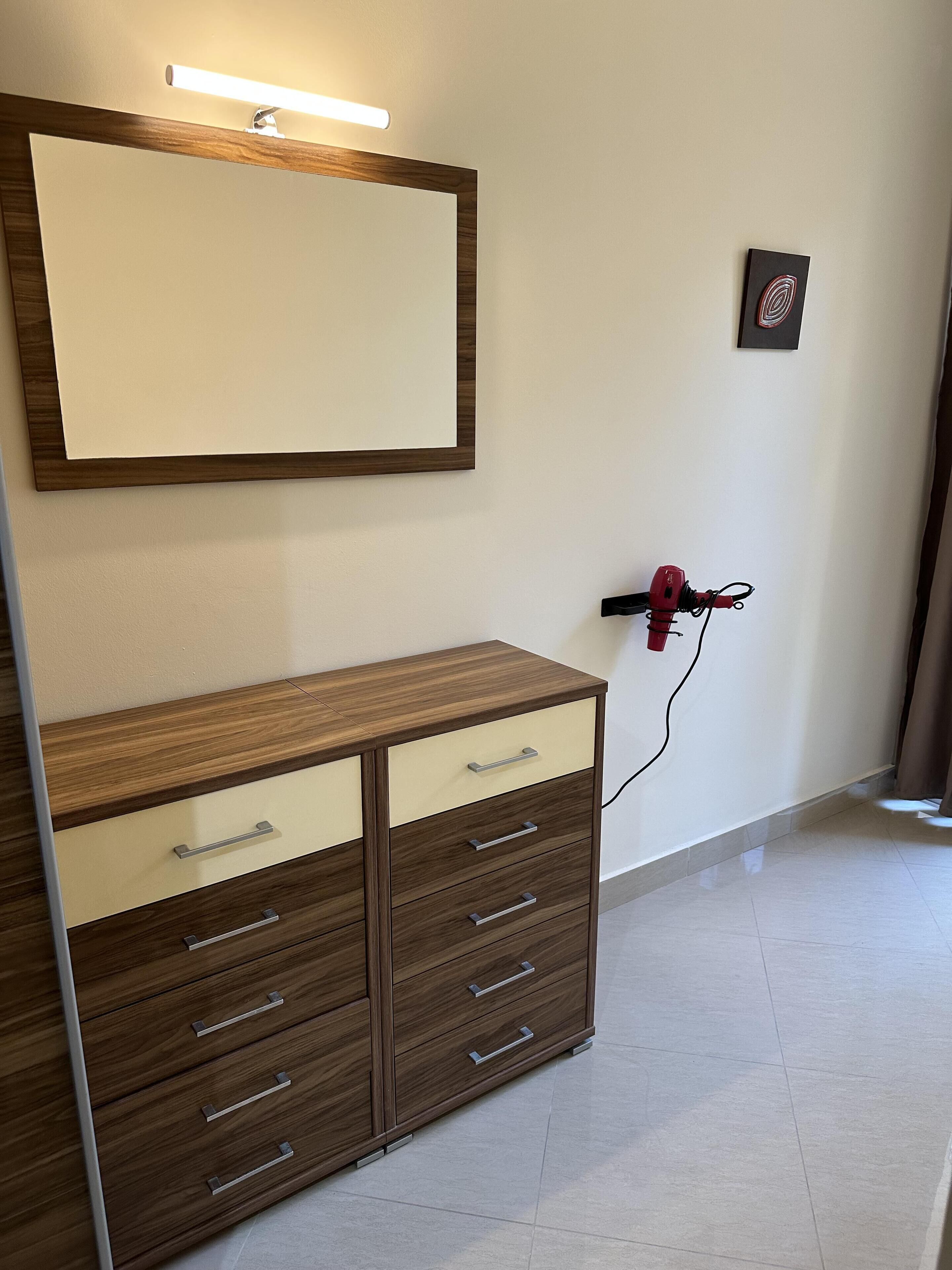 Una habitación con un aparador de madera con varios cajones y un espejo grande encima.
