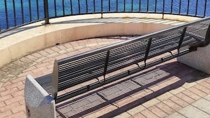 A waterfront promenade with a bench, a clear view of the sea, and a historic church in the background. - Ewa Apt - 3-bed Near Sliema - St Julians Seafront (Gzira)