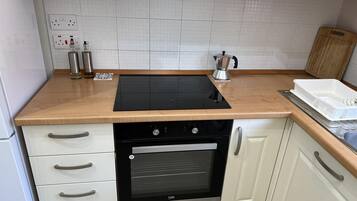 Una cocina compacta con tope de inducción negro, horno integrado y encimera de madera.