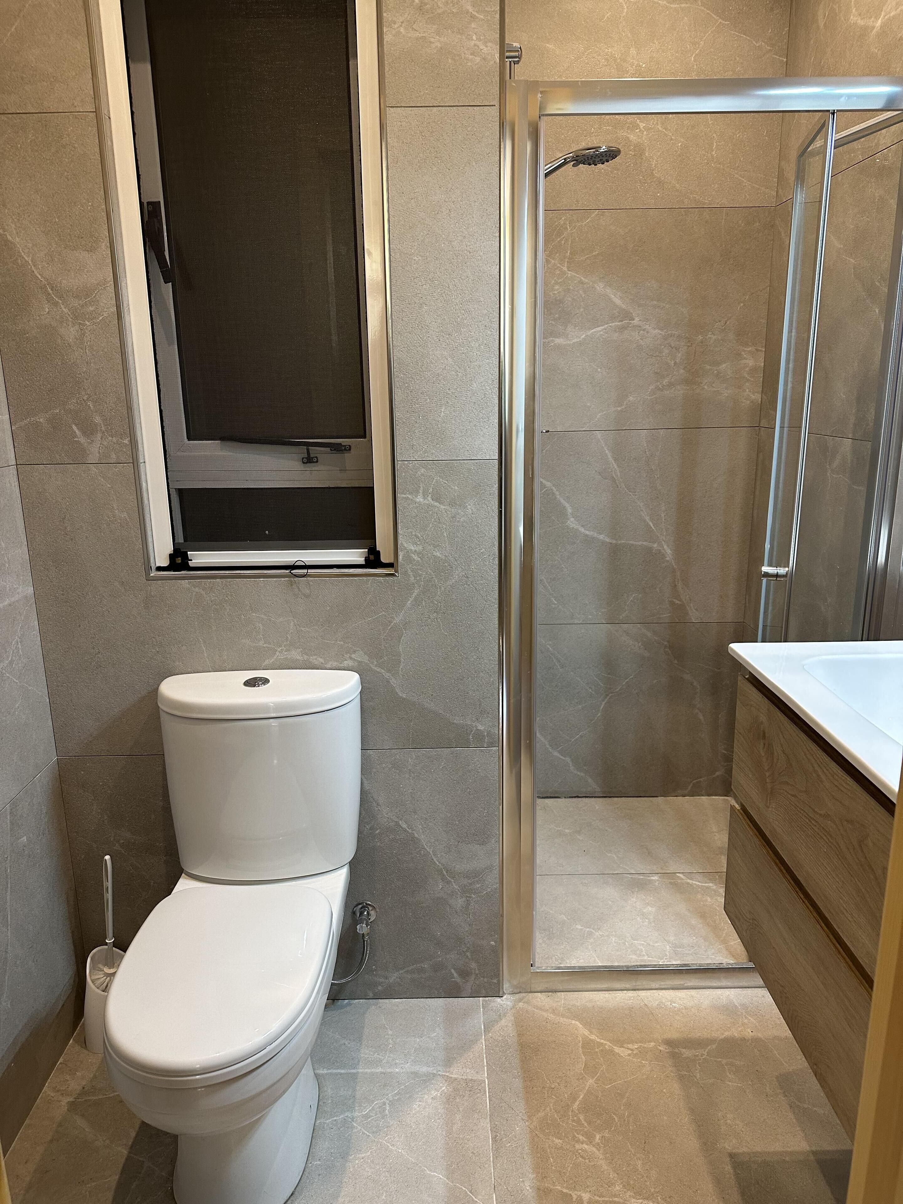 Un baño con inodoro, cabina de ducha y tocador con espejo.