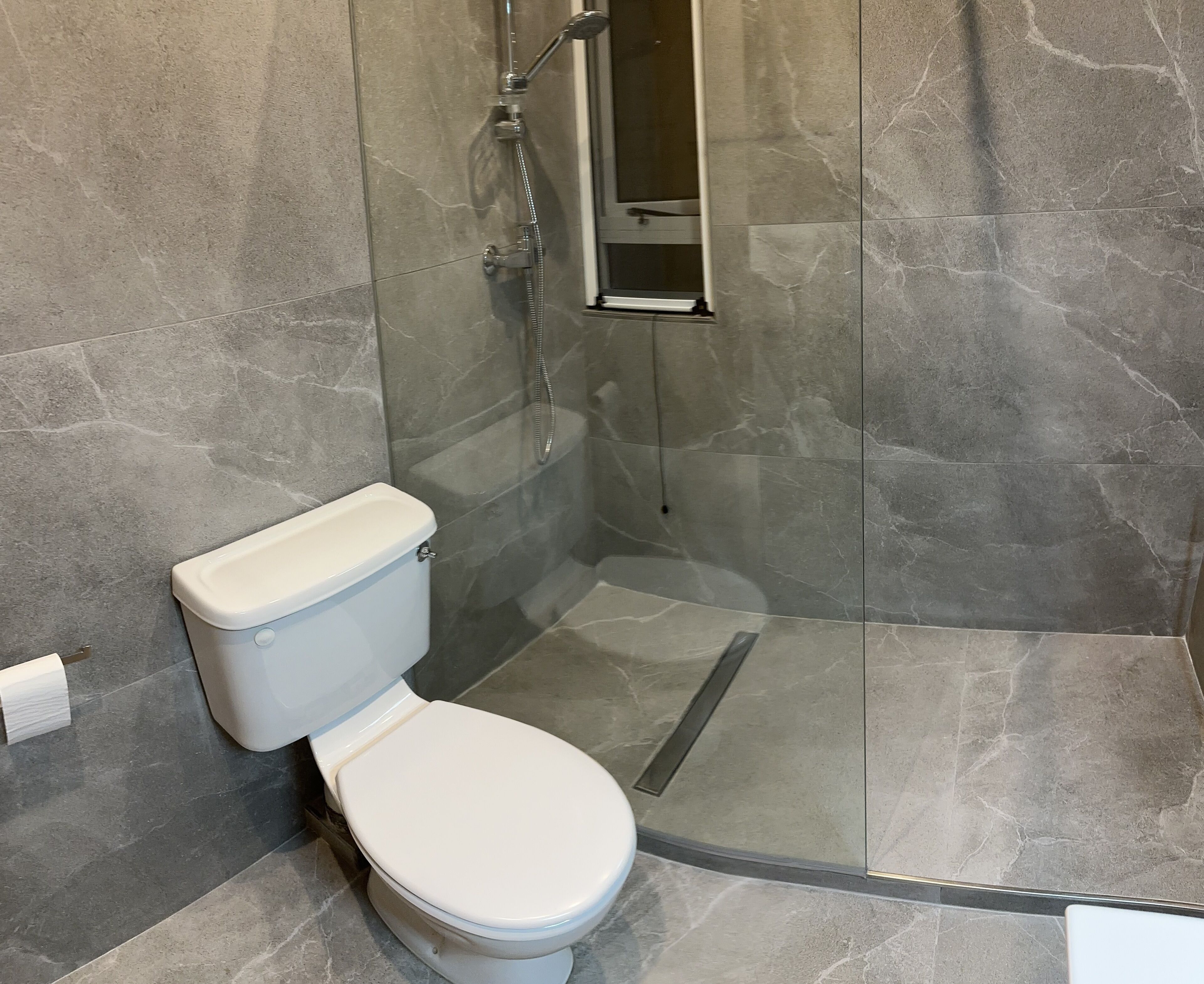 Un baño con inodoro, ducha y cabina de ducha de vidrio.