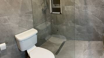 Un baño con inodoro, ducha y cabina de ducha de vidrio.