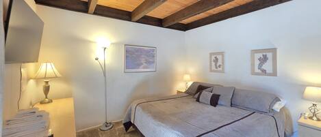 A bedroom with a bed, two bedside tables, a floor lamp, and wall art.
