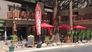 Un restaurante con terraza, sombrillas rojas y una bandera.