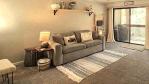 A living room with a grey sofa, a lamp, a small table, a basket, and a rug. - Taste Of Burgundy 1 Bedroom Condo by RedAwning (Incline Village)