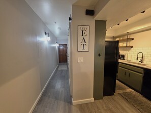 A hallway leading to a kitchen with a door marked 'LET'S EAT.' - Taste Of Burgundy 1 Bedroom Condo by RedAwning (Incline Village)