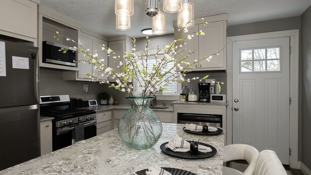 Een moderne keuken met een marmeren aanrecht, roestvrijstalen apparatuur en een vaas met bloemen.