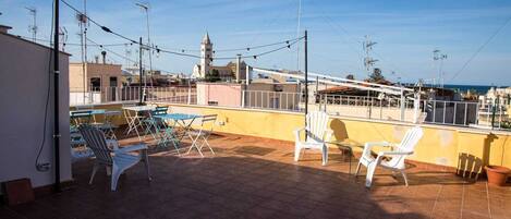A rooftop terrace with outdoor seating and a view of the cityscape.