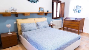 A bedroom with a bed, nightstand, dresser, and wall decorations.