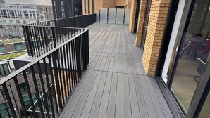Ein modernes Gebäude mit einer flachdachartigen Terrasse, großen Fenstern und einer Ziegel-Fassade.