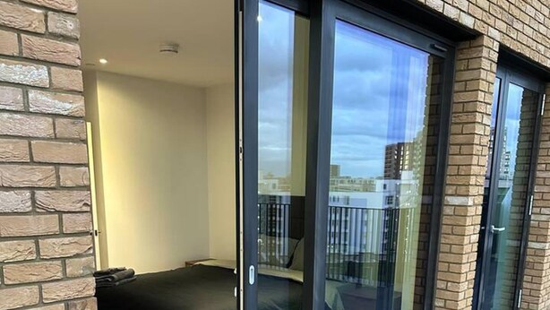 Ein modernes Schlafzimmer mit einer großen Schiebeglastür, die auf einen Balkon führt.