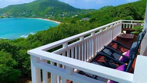 Un balcon avec vue sur une plage et des montagnes.