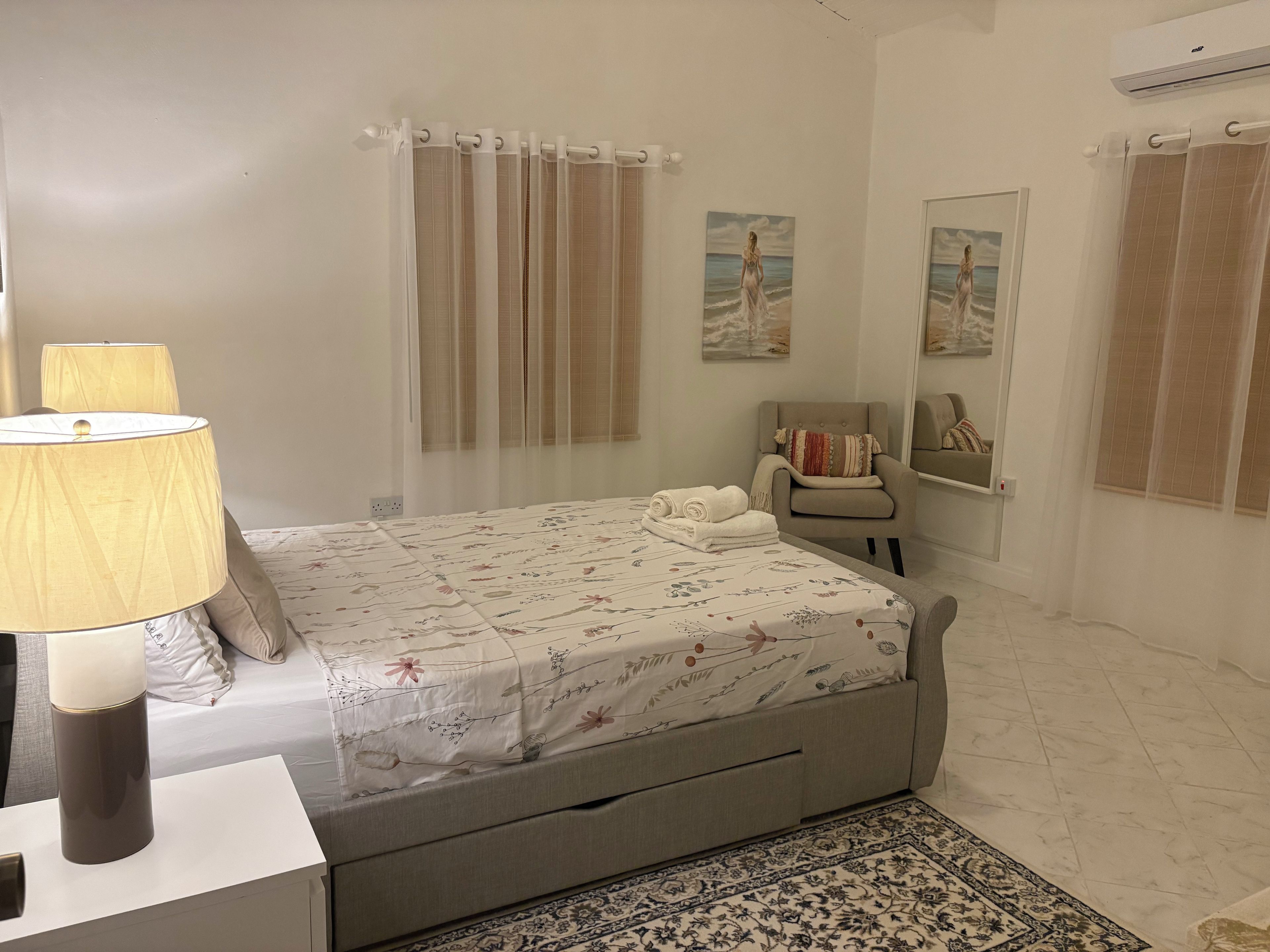 Quarto com cama, cadeira, luminária e tapete.