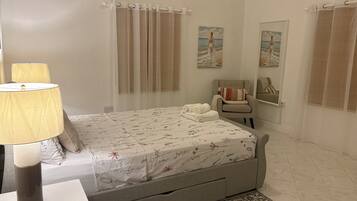 Quarto com cama, cadeira, luminária e tapete.