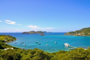 A coastal landscape with boats, a pier, and lush greenery. - Stunning 3 Bed Villa Overlooking Friendship Bay (Bequia Island)