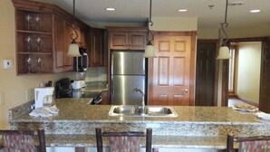 A kitchen with granite countertops, wooden cabinets, and a stainless steel refrigerator.