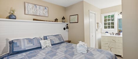 Ein Schlafzimmer mit Bett, Deckenventilator, einer an der Wand befestigten Ablage mit Dekorationen, einer Tür und einem Fenster.