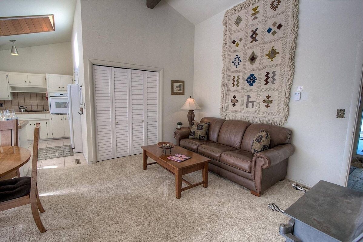 A living room with a brown leather sofa, a wooden coffee table, and a patterned rug.