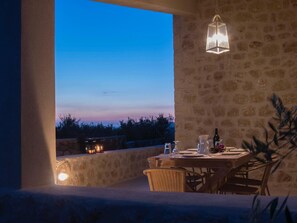Comedor al aire libre con paredes de piedra y una mesa dispuesta para dos, con vistas panorámicas.