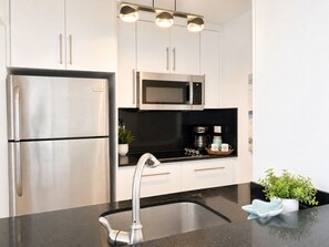 Een moderne keuken met roestvrijstalen apparatuur, een zwart aanrecht en een spoelbak.