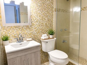 Een badkamer met een wit wastafelmeubel, een toilet en een douchecabine.