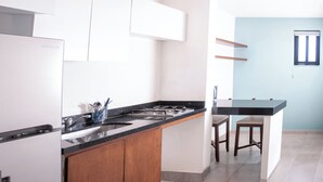 Una cocina con estufa integrada, un lavamanos, armarios de madera y una barra con taburetes.