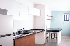Una cocina con estufa integrada, un lavamanos, armarios de madera y una barra con taburetes.