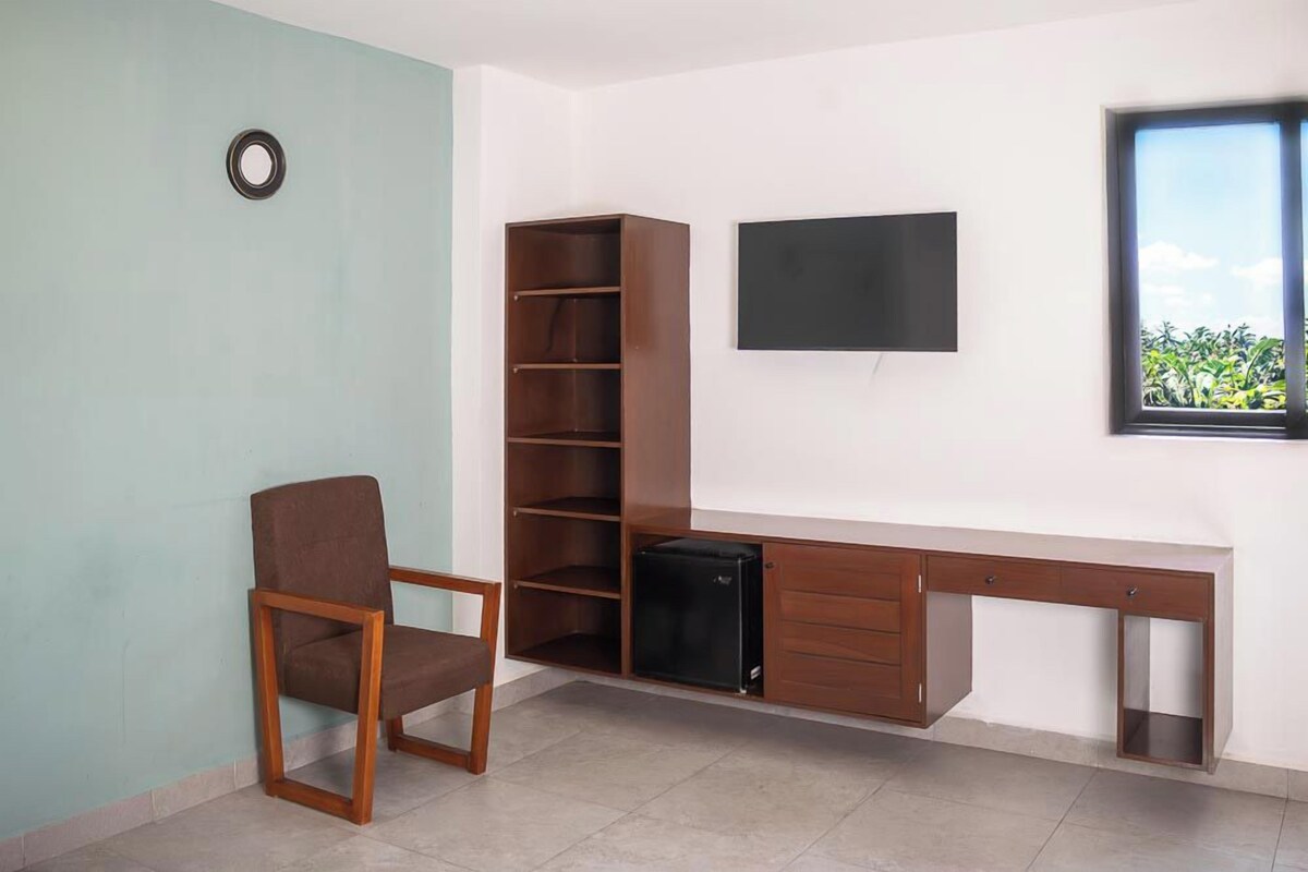 Una habitación con escritorio, silla, televisión y ventana con vistas.
