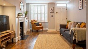 A living room with a fireplace, a television, a sofa, and a chair. - Trinity Cottage, Stratford-upon-Avon - sleeps 5 guests in 3 bedrooms (Stratford-upon-Avon)
