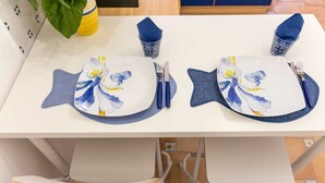 A dining table with two plates featuring blue and yellow floral designs, accompanied by blue napkins and cutlery.